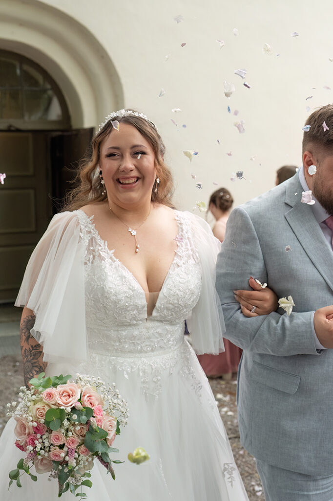 Bröllopspar som går ut ur kyrkan. De får rosblad kastade på sig.