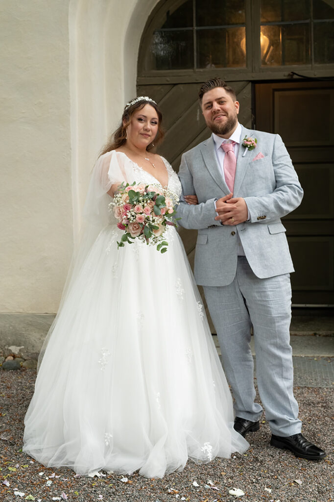 Bröllopspar som står utanför kyrkan de vigdes i.