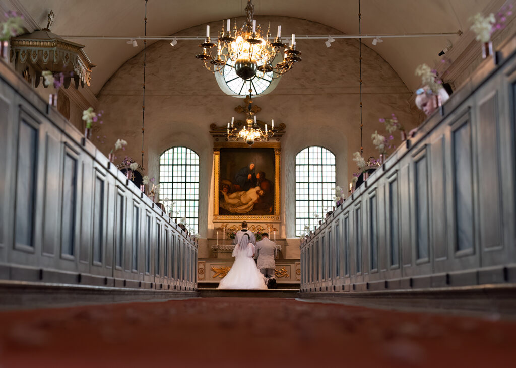 Brudparet som knäböjer vid altaret.