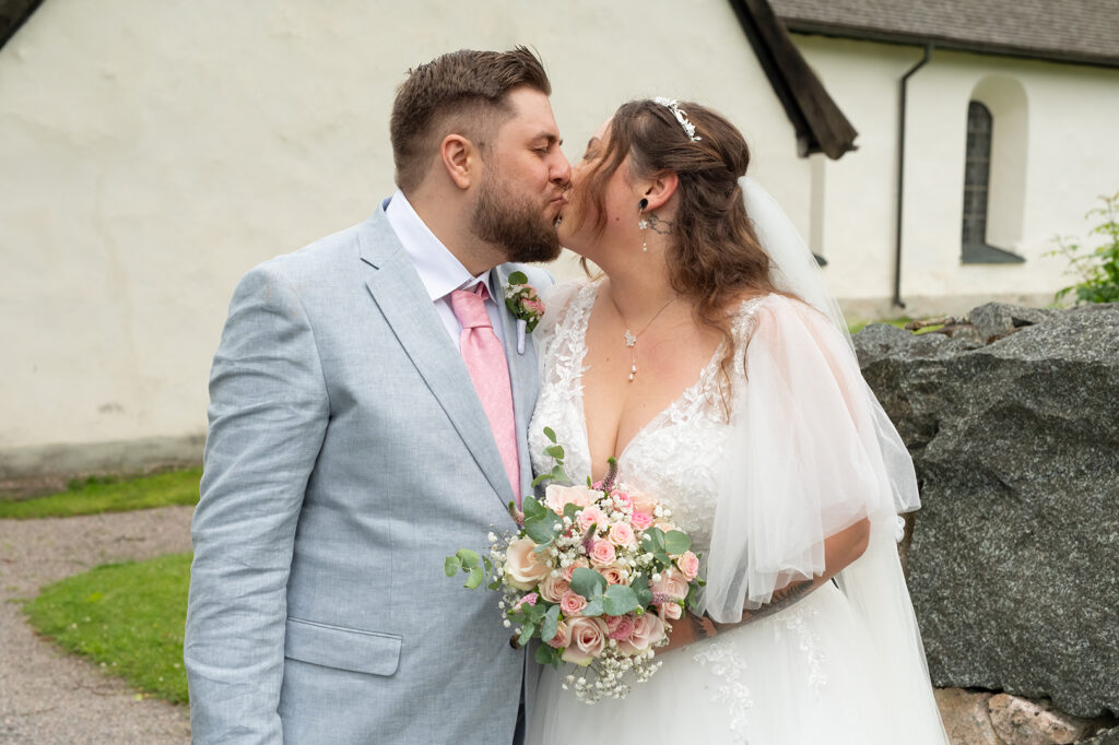 Brudparet som kysser varandra utanför kyrkan.