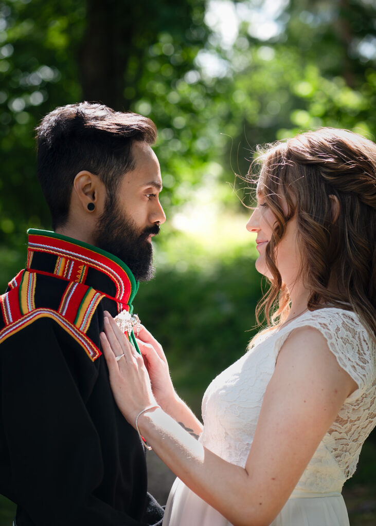 Porträtt av brudparet som står vända mot varandra. Vackert motljus.