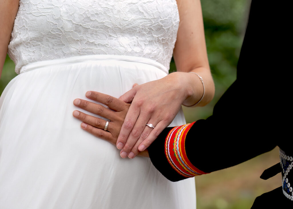 Maken håller handen på brudens mage. hon är gravid.